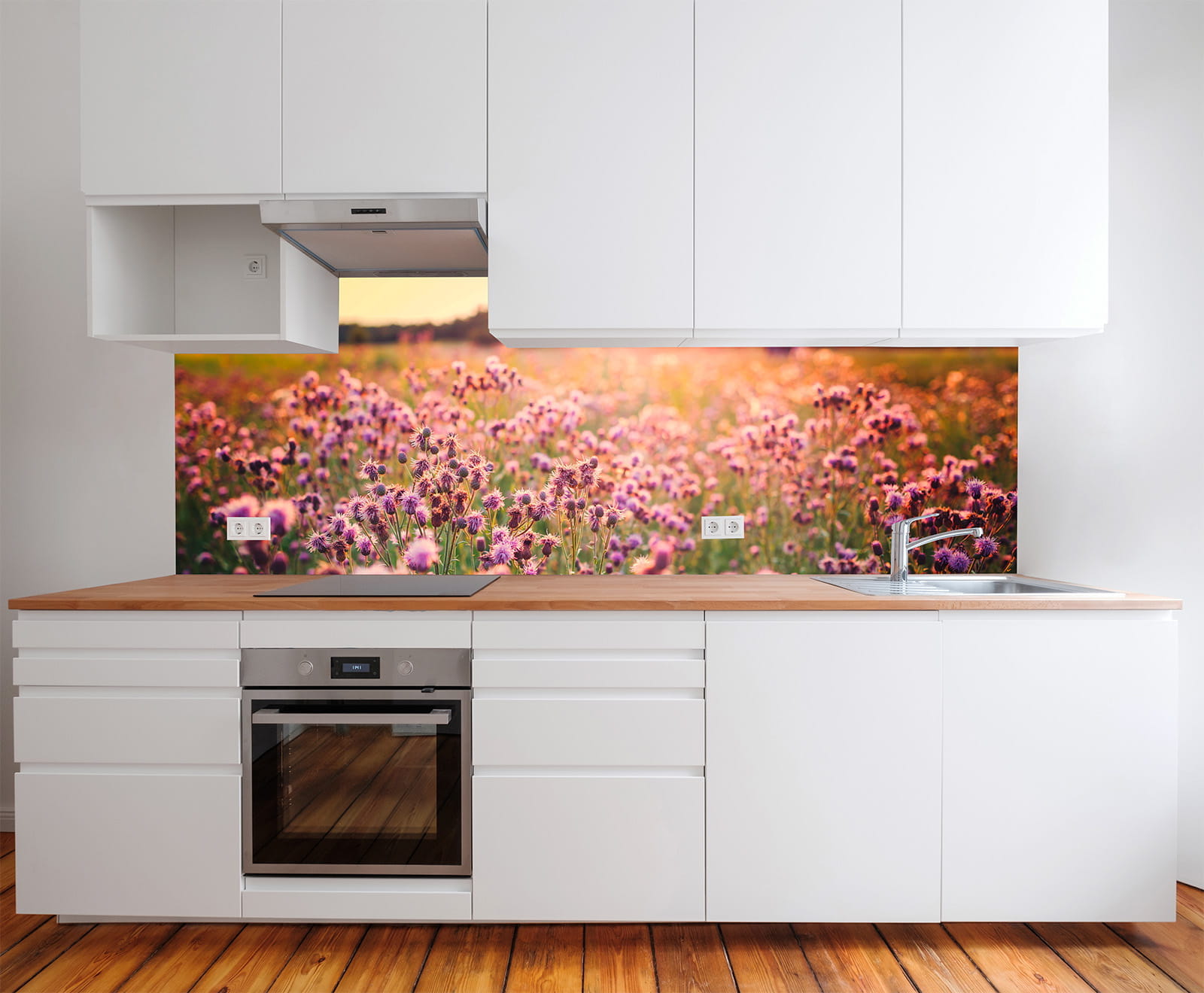 Küche mit weißen Schränken und Holzarbeitsplatte, im Hintergrund ein Wandbild mit einer Blumenwiese.