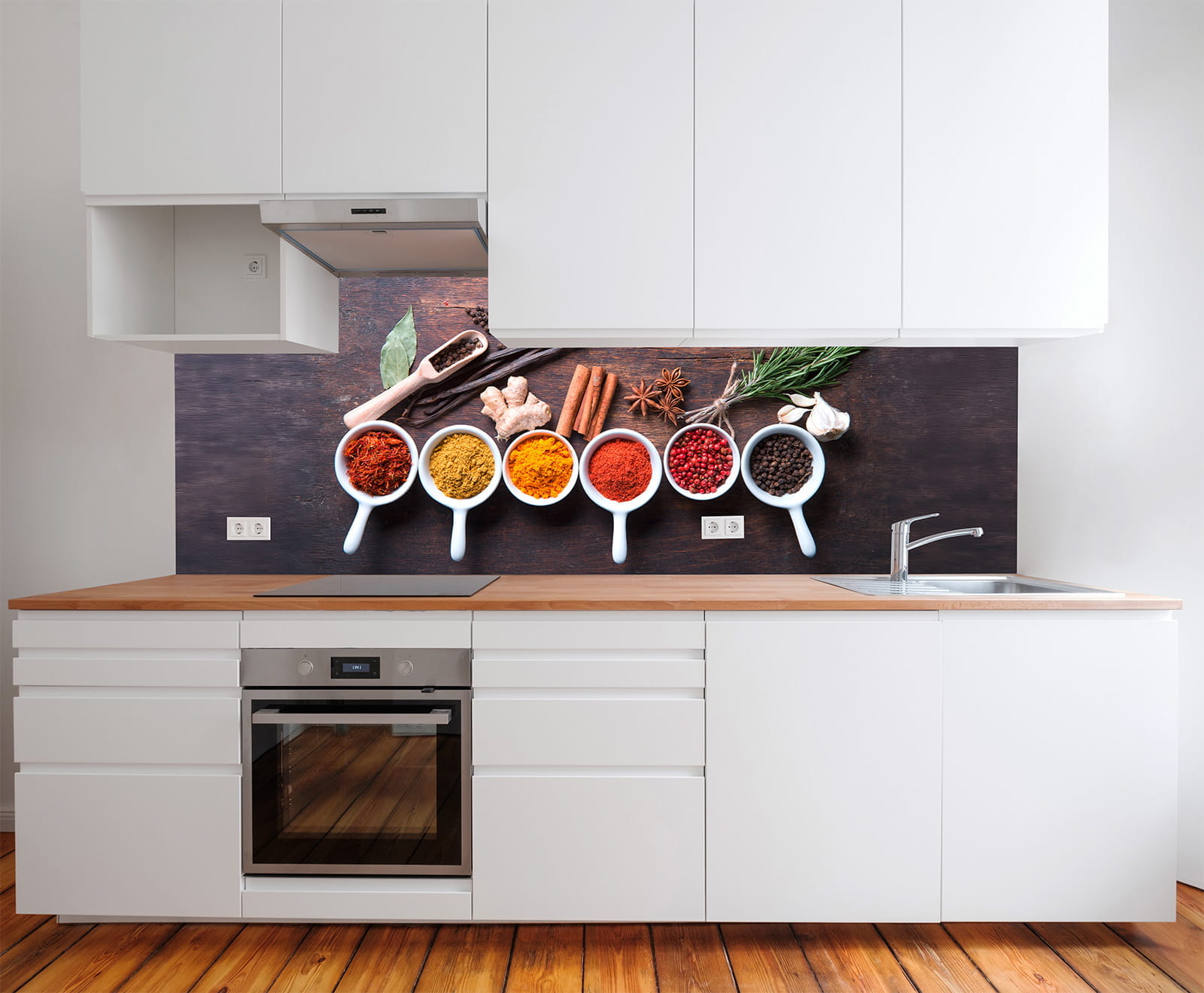 Küchenzeile mit weißen Schränken und Holzarbeitsplatte, dekoriert mit bunten Gewürzen und Kräutern in Schalen.