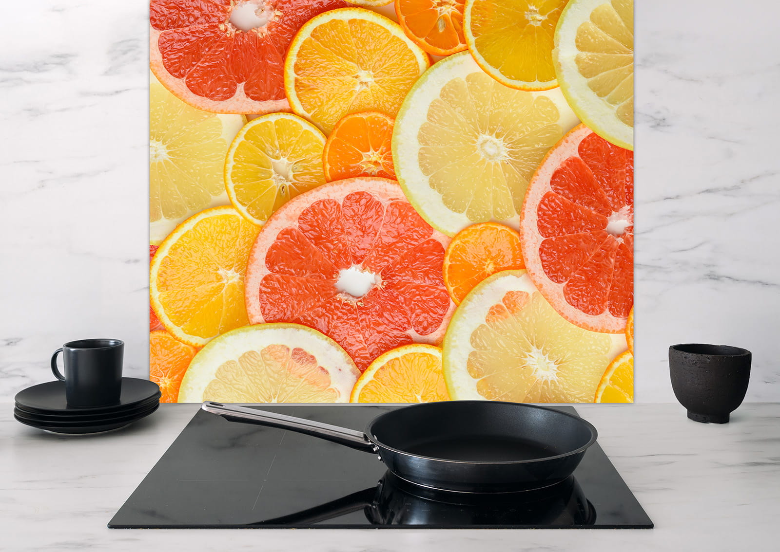Spritzschutz Zitrusscheiben aus Kunststoff mit bunten Zitrusfrüchten, auf einer modernen Küchenarbeitsplatte mit Pfanne und Geschirr.