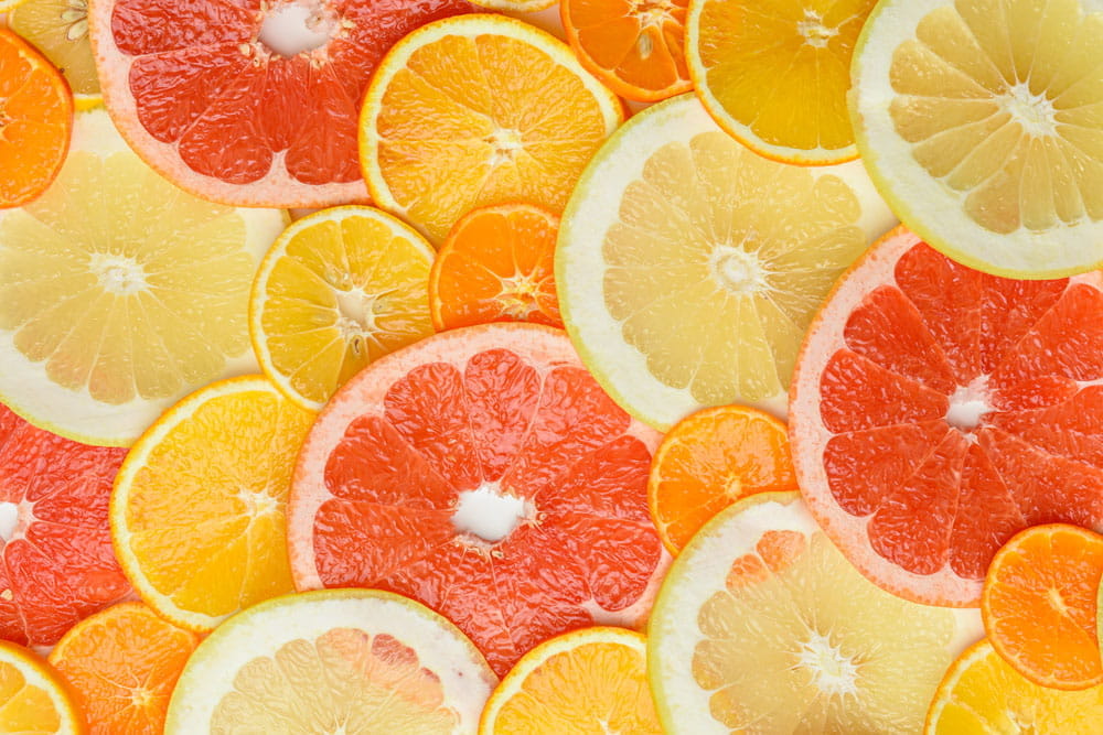 Scheiben von Zitrusfrüchten wie Grapefruit, Orange und Zitrone auf einem hellen Hintergrund.