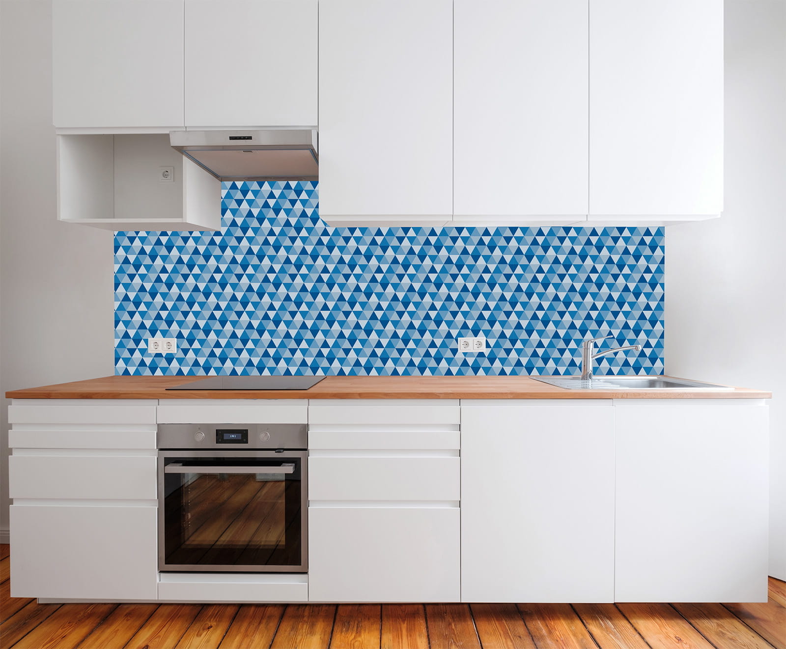 Küche mit weißen Schränken und Holzarbeitsplatte, Rückwand aus Mosaikfliesen mit blauen Dreiecken.