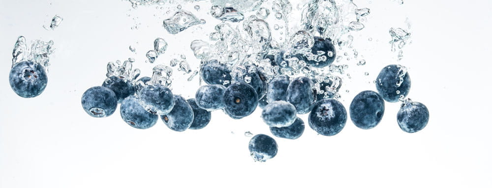 Frische Blaubeeren spritzen in Wasser, umgeben von Blasen.